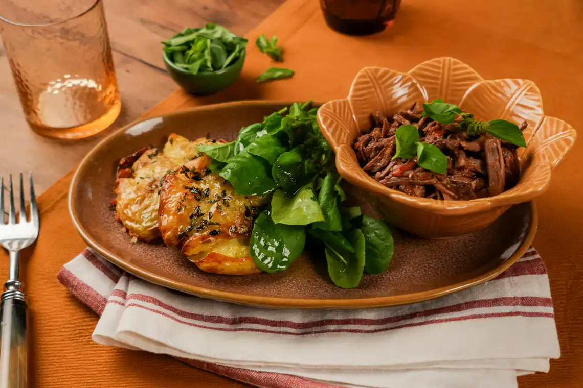 ragu servido com batata ao murro assada e agrião
